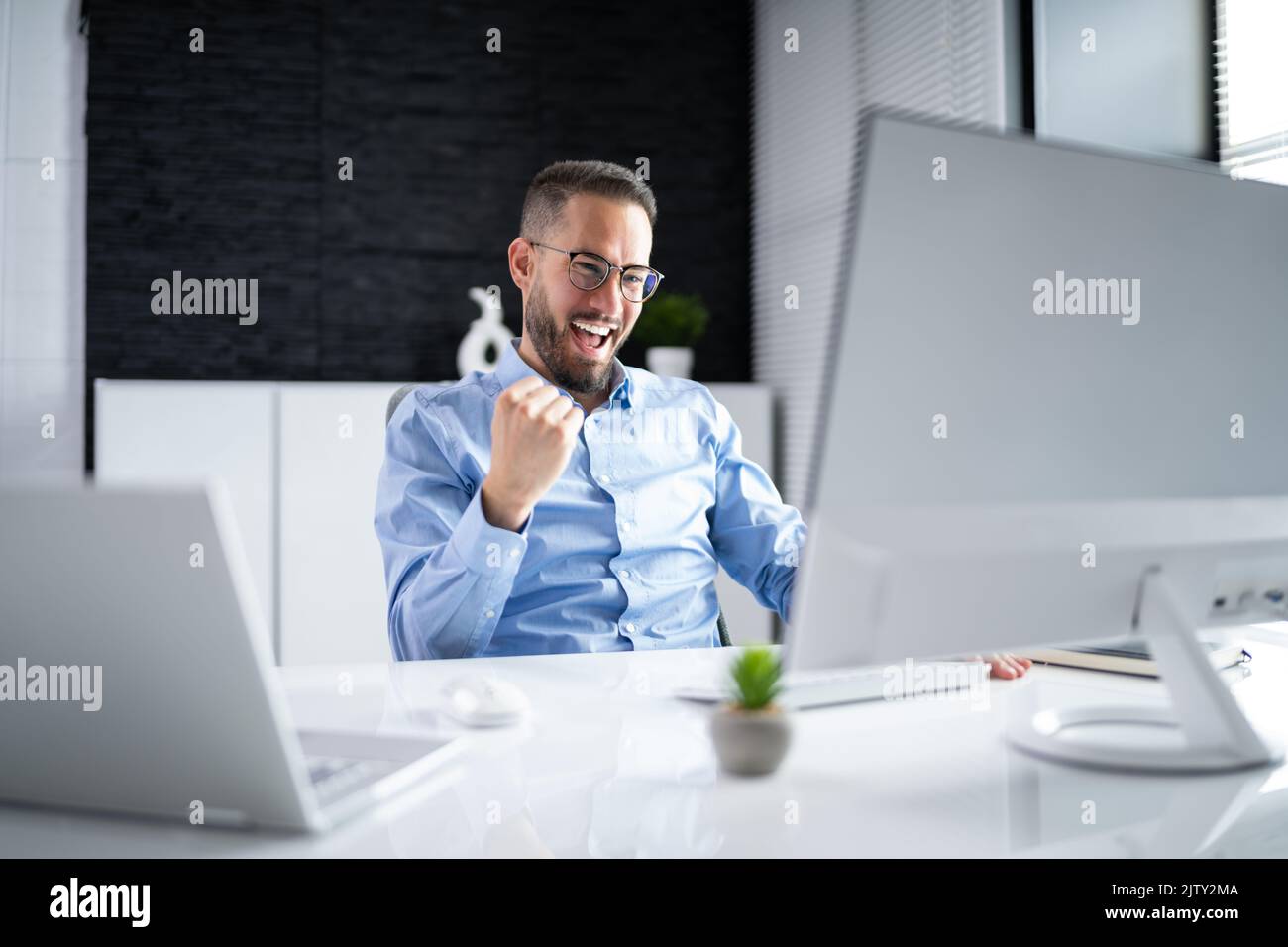 Happy Man With Arms Raised Feiert Sieg Am Computer Stockfoto