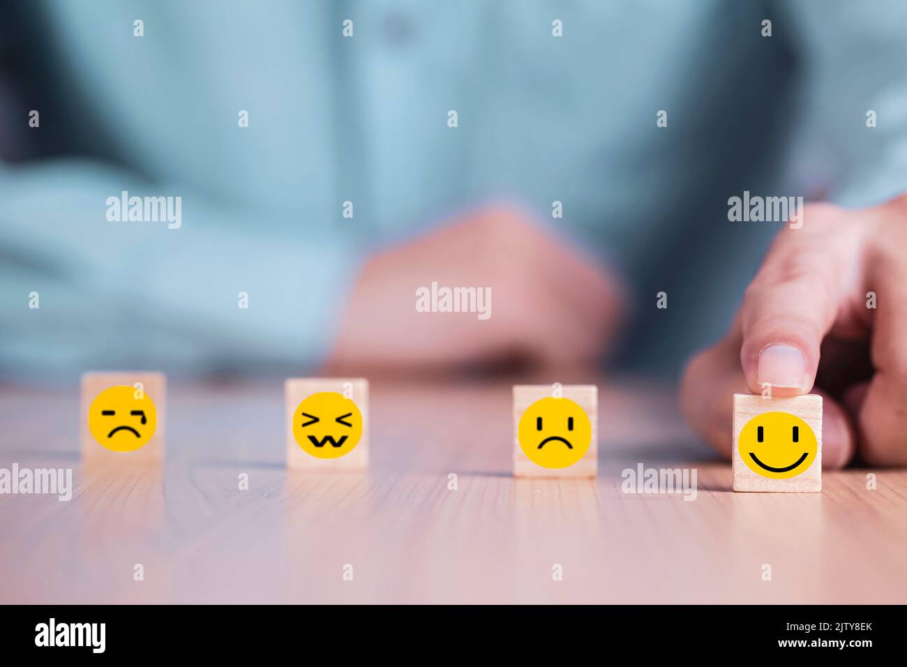 Geschäftsmann wählt ein Lächeln Emoticon Symbole Gesicht glücklich Symbol auf Holzblock , Dienstleistungen und Kundenzufriedenheit Umfragekonzept Stockfoto