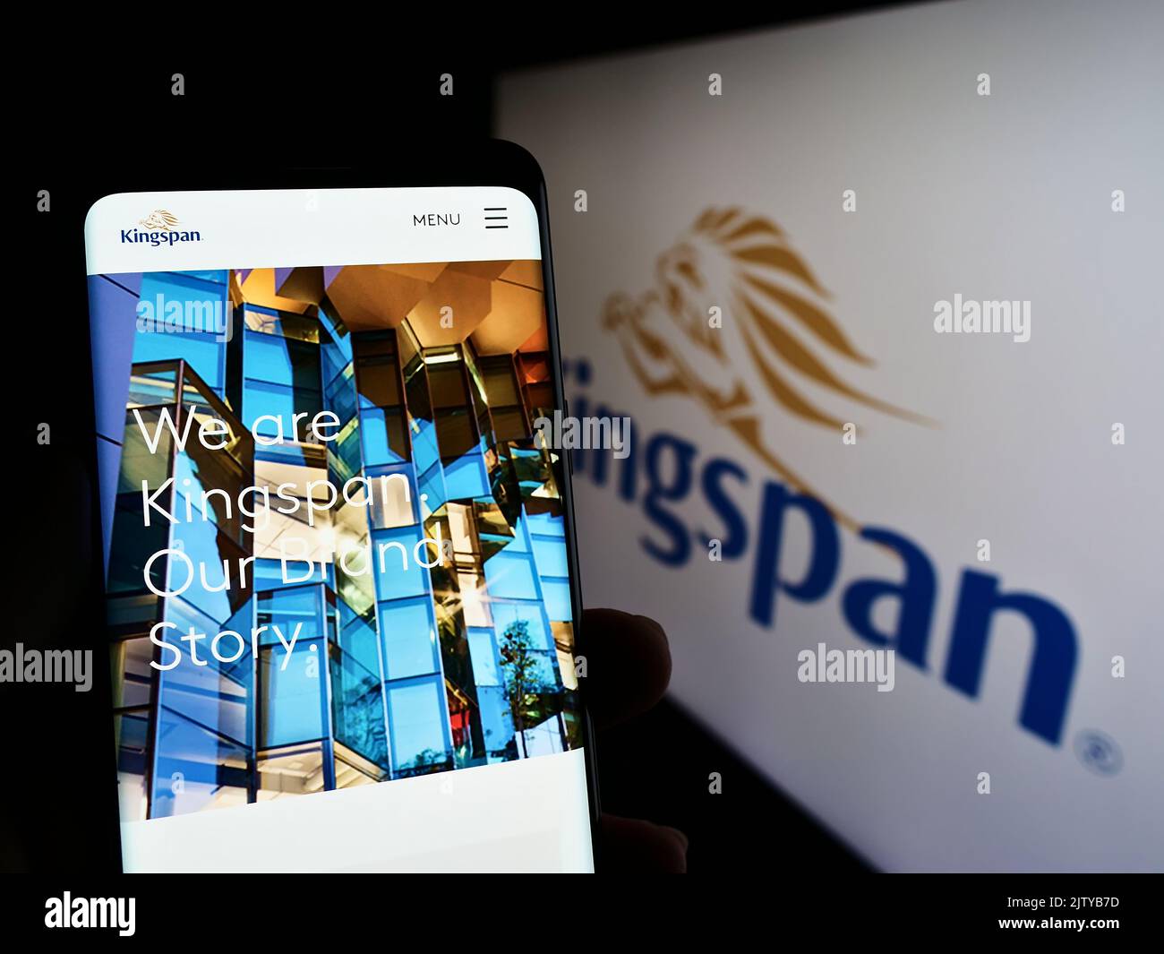 Person, die Mobiltelefon mit der Webseite des Baustoffunternehmens Kingspan Group plc auf dem Bildschirm mit Logo hält. Konzentrieren Sie sich auf die Mitte des Telefondisplays. Stockfoto