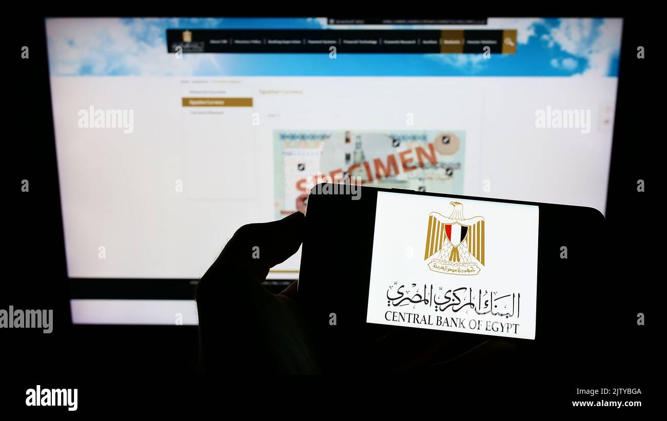 Person, die Mobiltelefon mit dem Logo der Zentralbank von Ägypten (CBE) auf dem Bildschirm vor der Webseite hält. Konzentrieren Sie sich auf die Telefonanzeige. Stockfoto