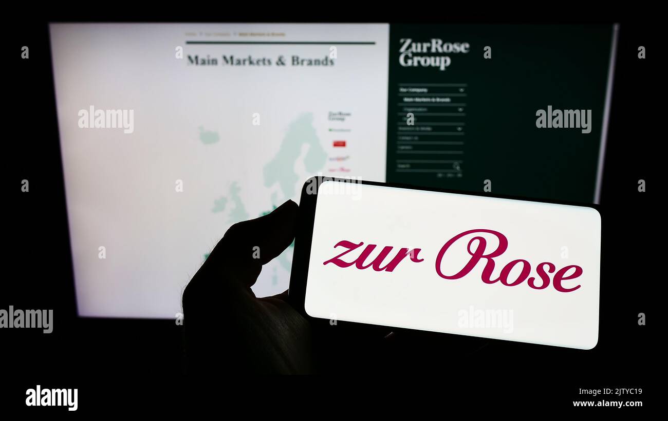 Person, die Smartphone mit Logo des Schweizer Pharmaunternehmens zur Rose Group AG auf dem Bildschirm vor der Website hält. Konzentrieren Sie sich auf die Telefonanzeige. Stockfoto