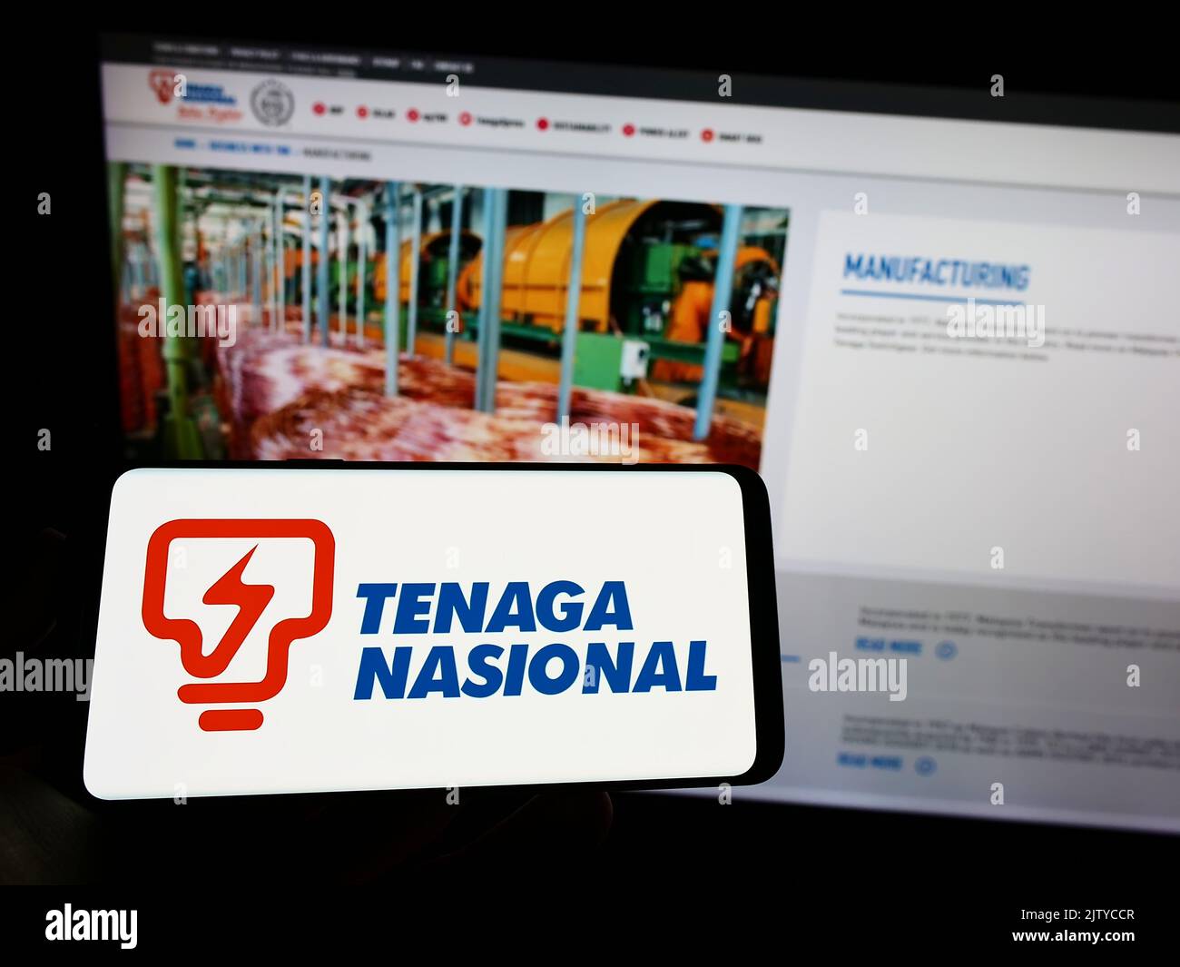 Person mit Mobiltelefon und Logo des malaysischen Unternehmens Tenaga Nasional Berhad (TNB) auf dem Bildschirm vor der Webseite. Konzentrieren Sie sich auf die Telefonanzeige. Stockfoto