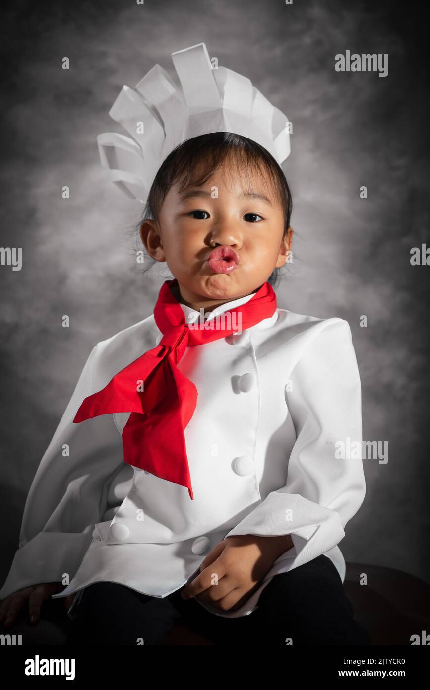 Ein kleiner Koch kocht mit poutenden Lippen Porträt. Asiatisch-philippinisches Mädchen. Stockfoto