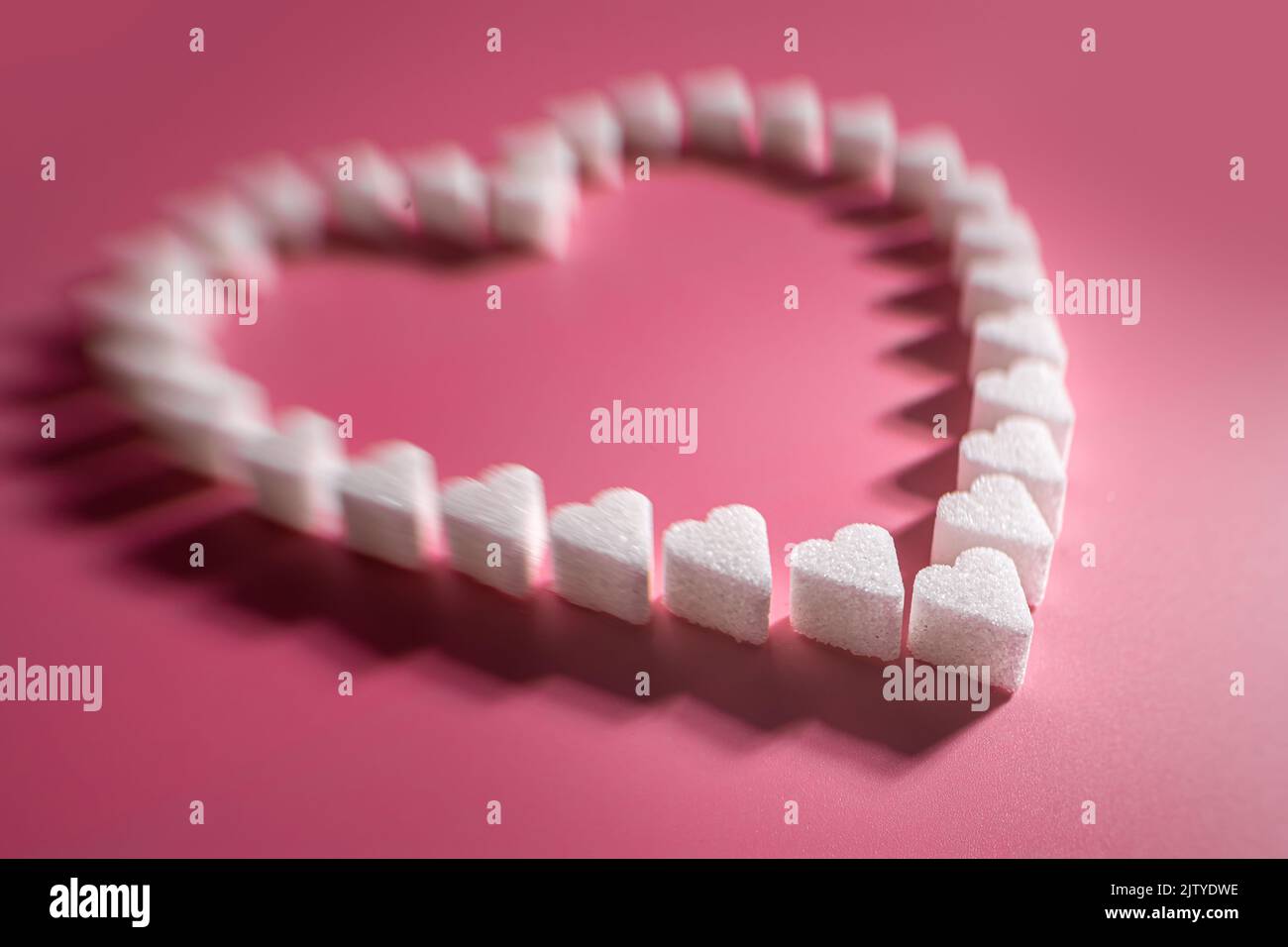 Herz aus Zuckerwürfelherzen auf rosa Hintergrund, selektiver Fokus Stockfoto