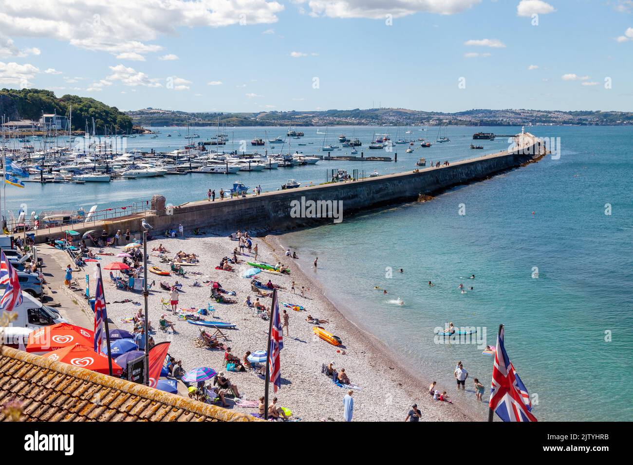 Ein belebtes Brixham Beach mit dem Wellenbrecher im Hintergrund. Stockfoto