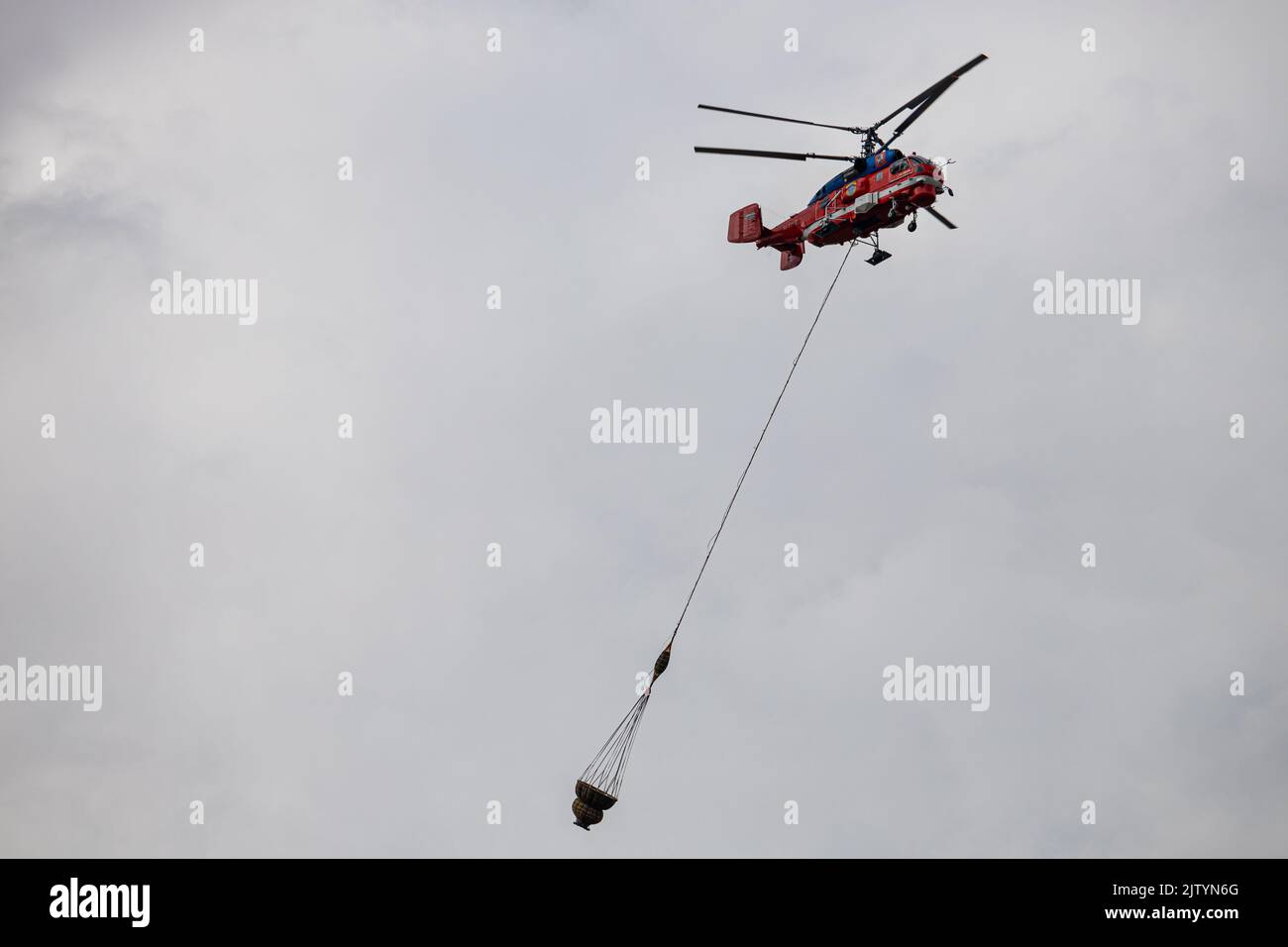 Der Hubschrauber transportiert Fracht in einem Hängekorb Stockfoto