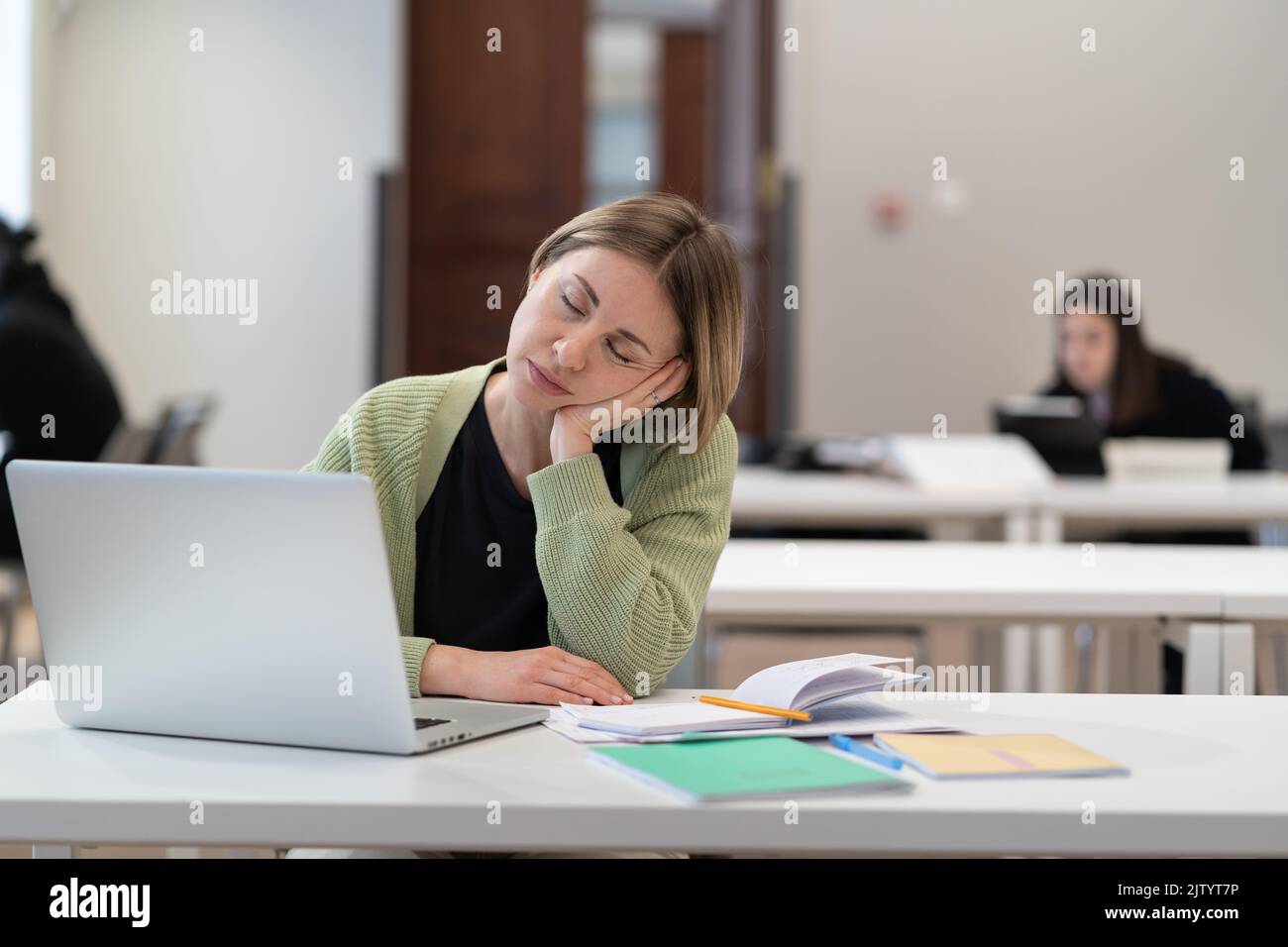 Erschöpfte müde Studentin mittleren Alters, die während des Studiums in der Erwachsenenbildungsklasse einschläft Stockfoto