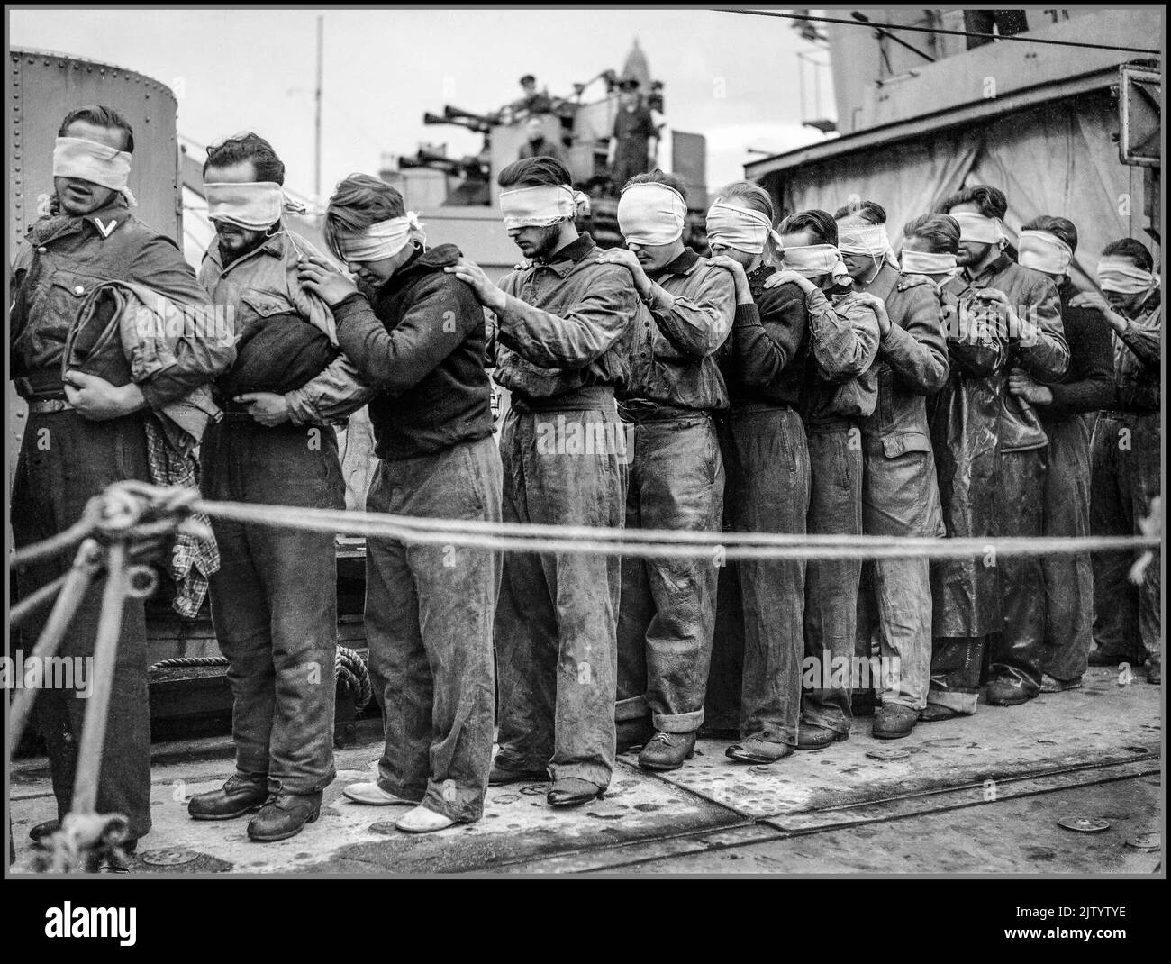 WW2 Nazi-U-Boot gefangen & mit verbundenen Matrosen Kriegsgefangene mit ihren Entführer die Royal Navy während des Zweiten Weltkriegs verhüllte U-Boot-Gefangene, die vom Zerstörer HMS ORIBI oder HMS ORWELL in Greenock auf dem Weg zur Internierung ausschifften. Sie sind Überlebende von U-Booten, die von Küstenkommandoflugzeugen versenkt und von Zerstörern abgeholt wurden. WW2 Zweiter Weltkrieg Stockfoto