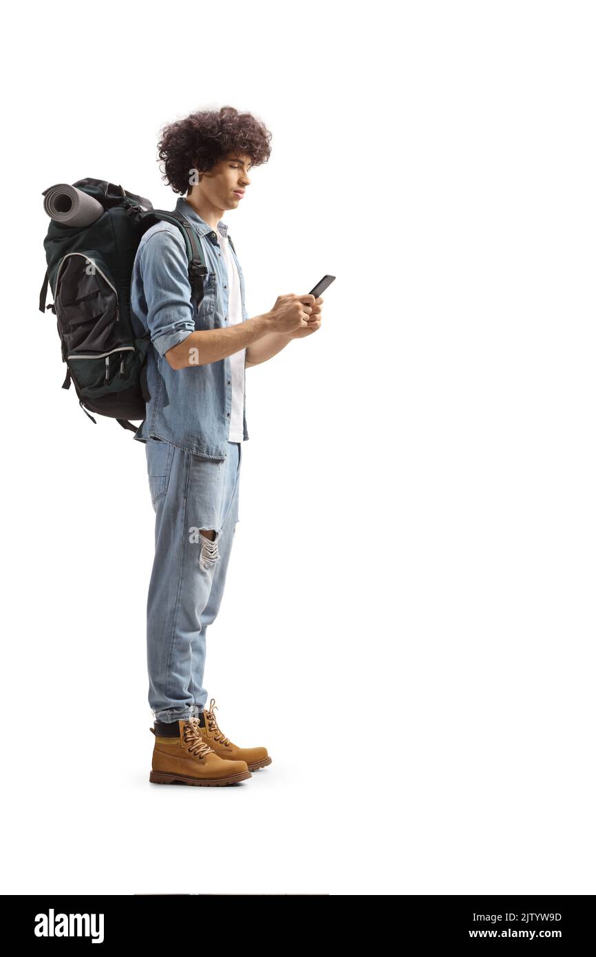 In voller Länge Profil eines jungen männlichen Backpacker stehend und mit einem Smartphone isoliert auf weißem Hintergrund Stockfoto