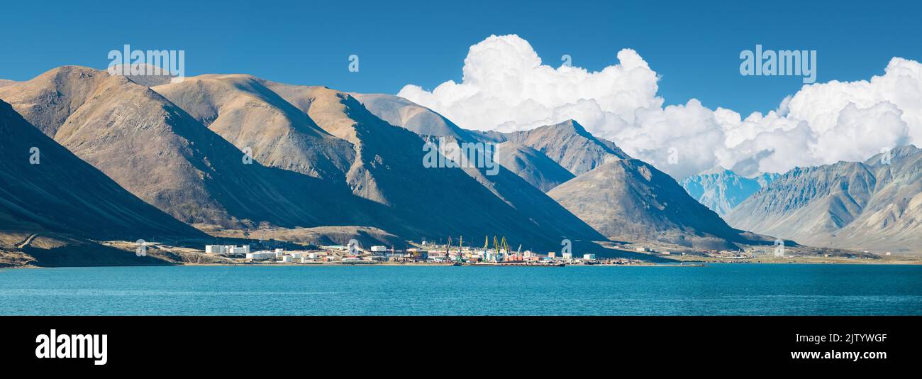 Gebirge, blauer Himmel mit Wolken und Egvekinot Dorf in Tschukotka. Stockfoto