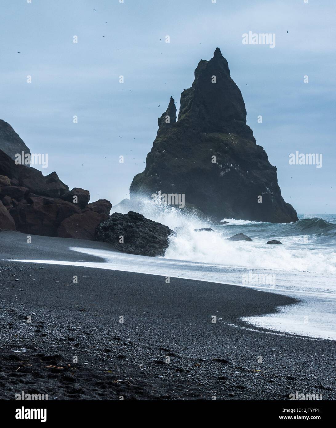 Basaltmeer-Stacks, eingerahmt vom schwarzen Sand und den Wellen des Atlantischen Ozeans, Reynisfjara Beach, Südisland Stockfoto