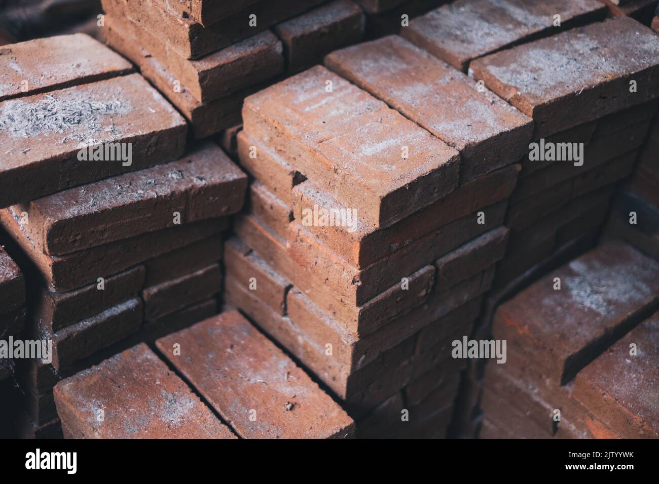 Stapel von neu hergestellten festen Ziegelsteinen aus Lehm (Backerde), die für die Landschaftsgestaltung und andere Gebäude- und Bauzwecke verwendet werden. Selektiver Fokus. Stockfoto
