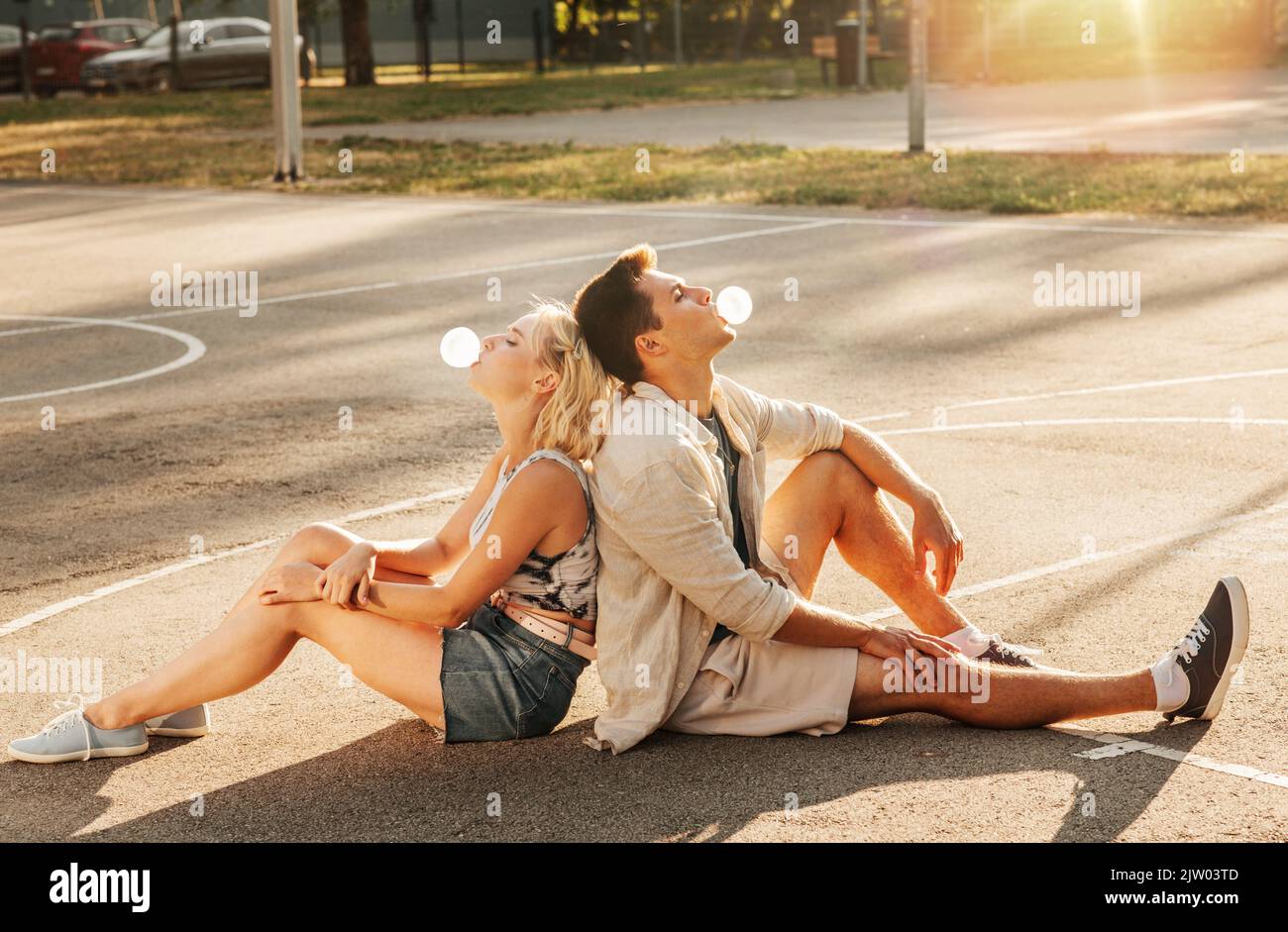Pärchen sitzt auf dem Boden und bläst Blasengummis Stockfoto