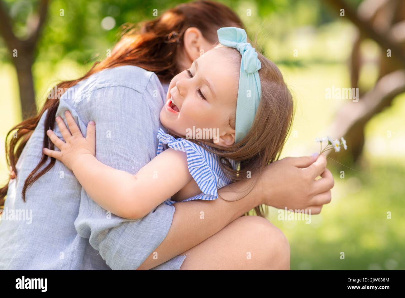 Glückliche Mutter und Tochter mit Blumen im Park Stockfoto