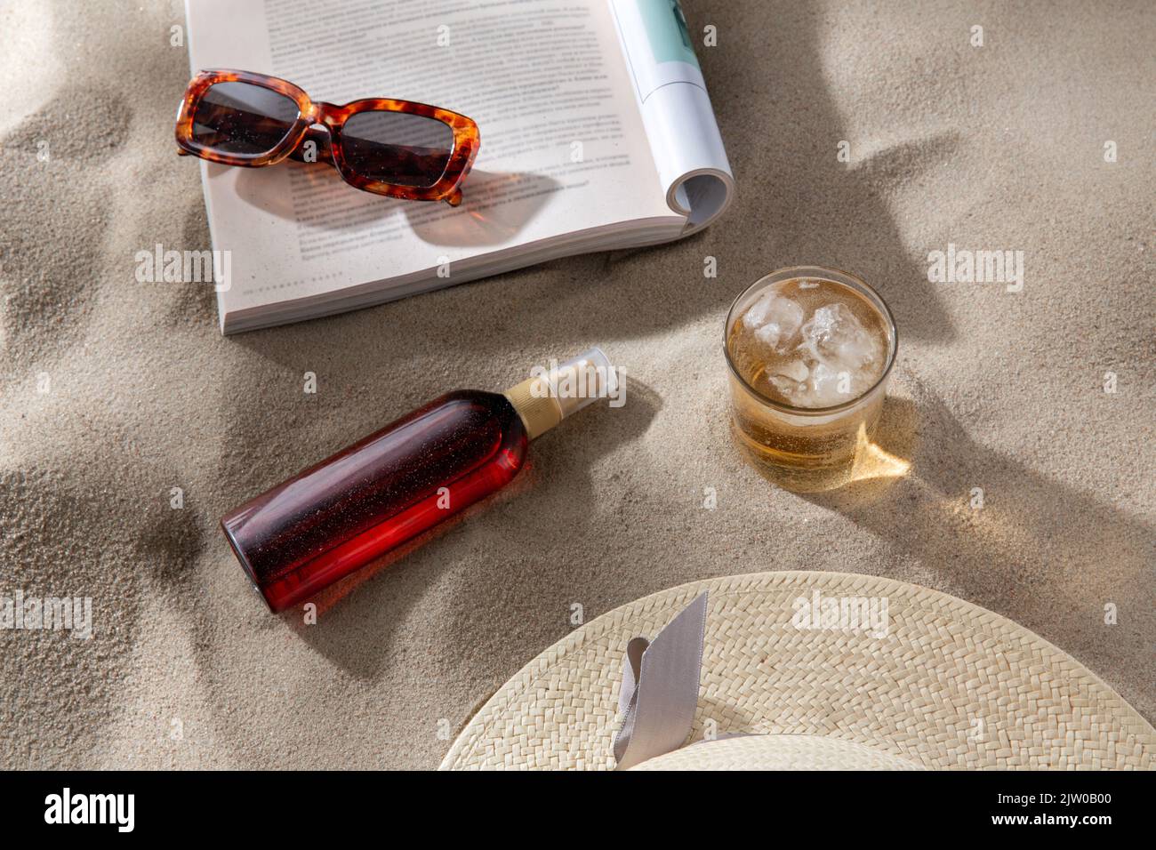 Magazin, Sonnenbrillen und Sonnencreme auf Strandsand Stockfoto