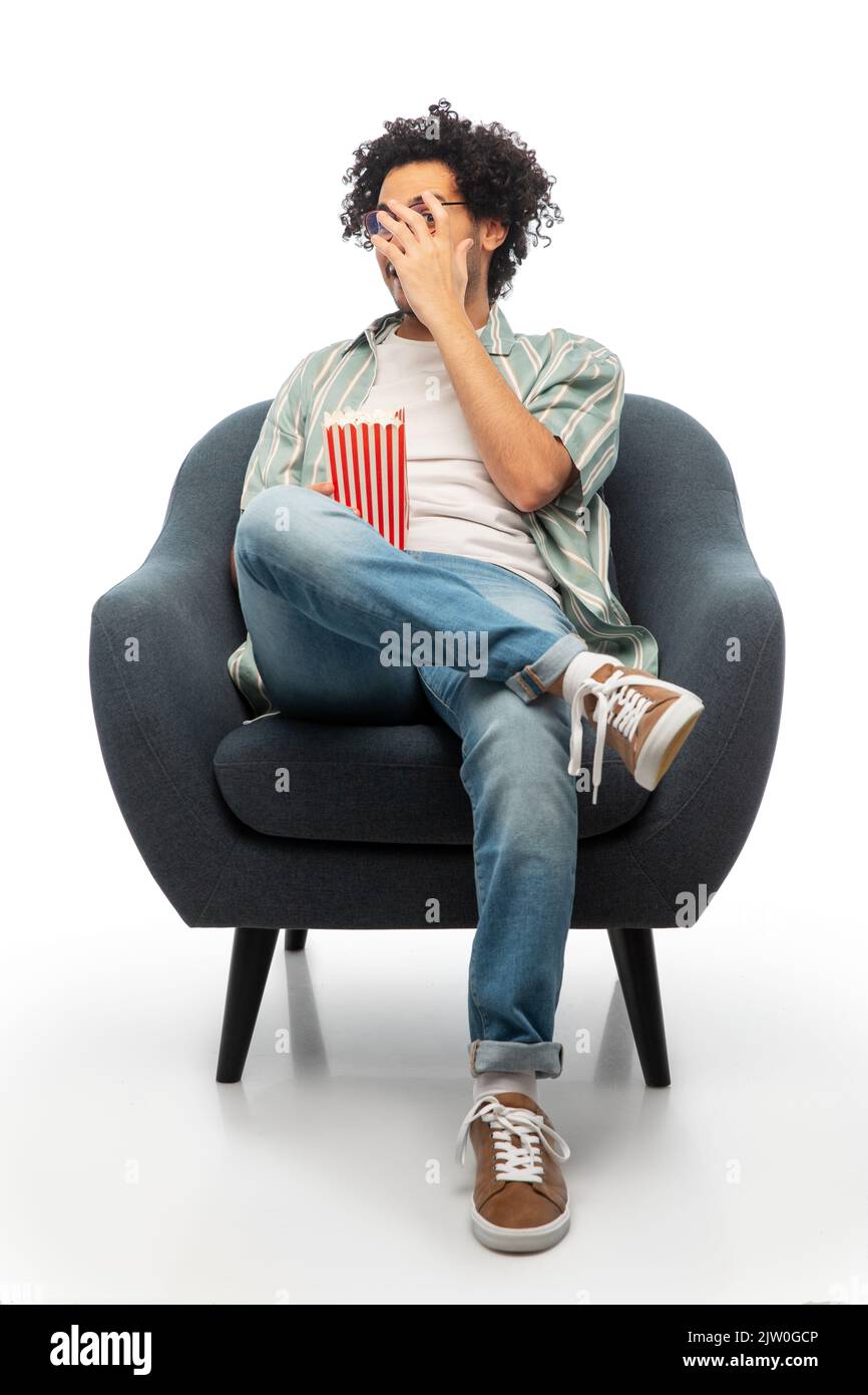 Mann mit Popcorn, der sich einen Film ansieht und auf einem Stuhl sitzt Stockfoto
