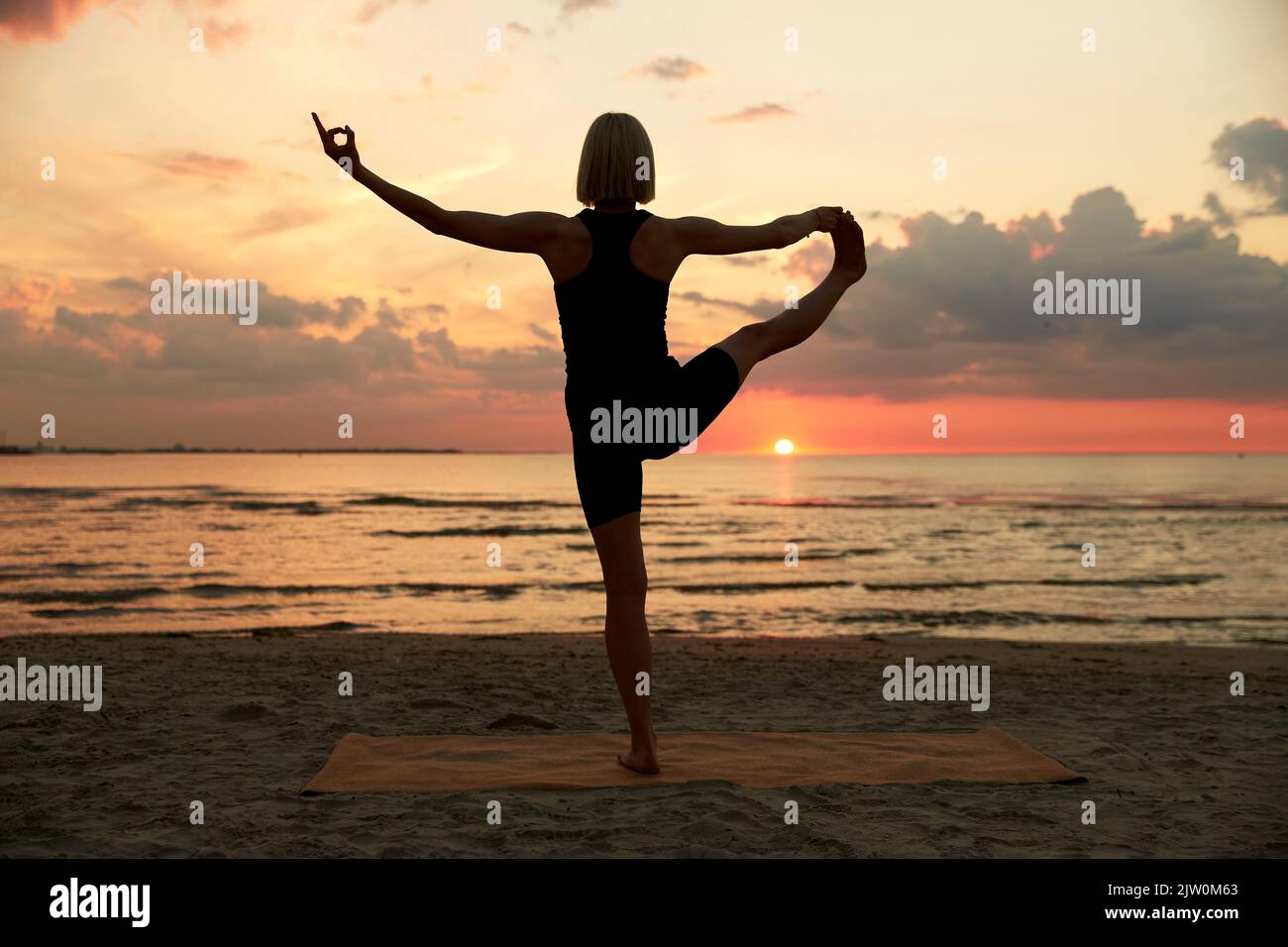 Frau, die Yoga von Hand zu Fuß am Strand macht Stockfoto