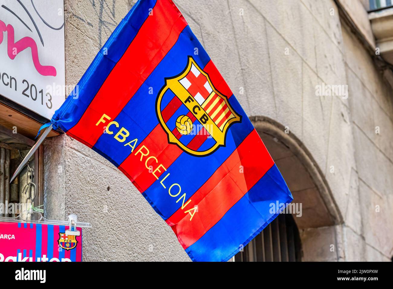 Blick aus der Nähe auf einen Football Club Barcelona oder FCB. Das Textilsymbol winkt im Wind vor der Tür eines privaten kleinen Souvenirladens. Stockfoto