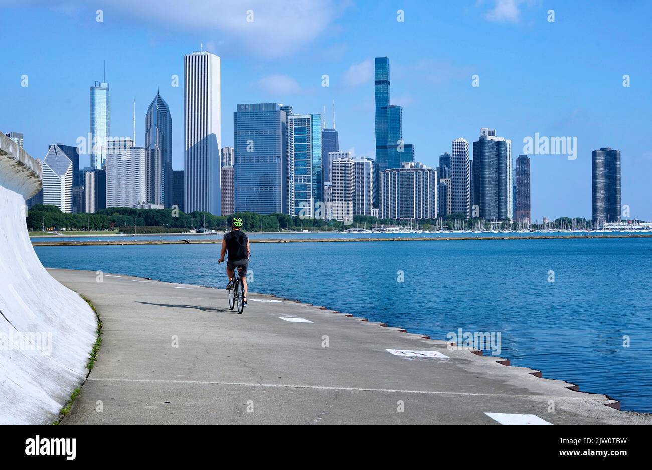Chicago - August 2022: Ein Radfahrer fährt auf Chicagos Uferweg mit Blick auf die Skyline der Stadt Stockfoto