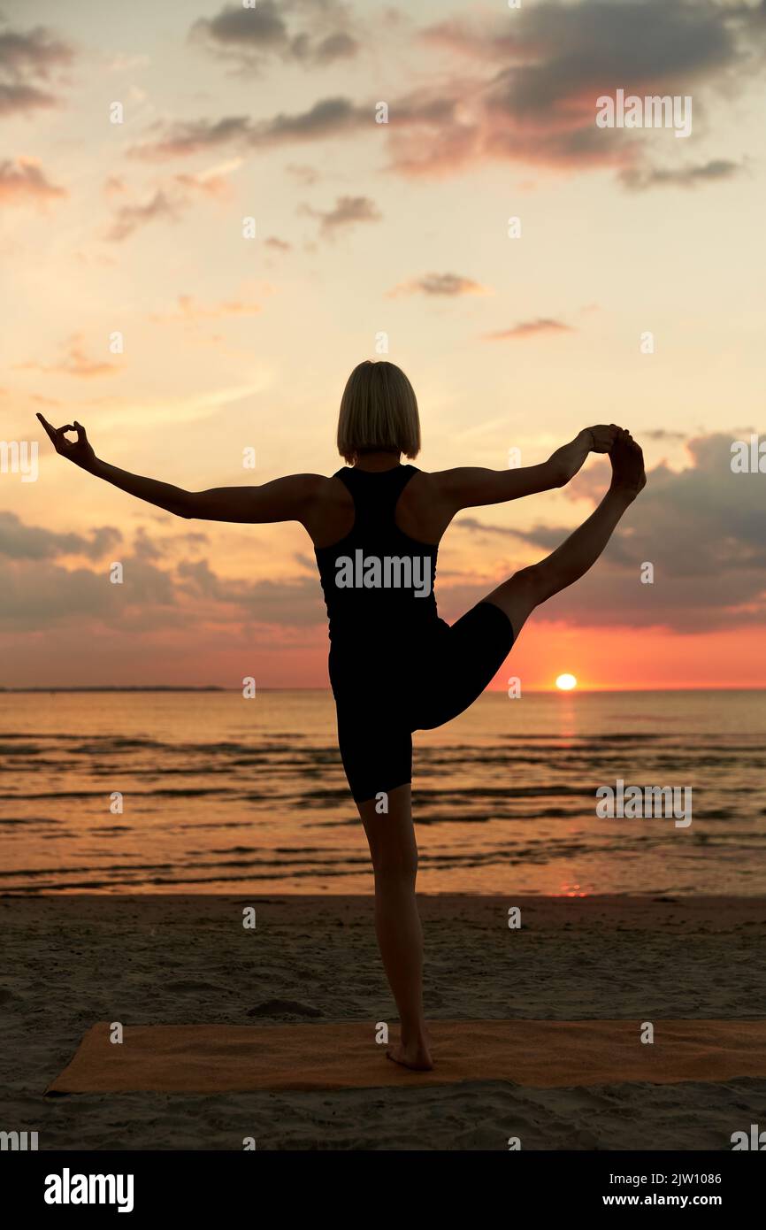 Frau, die Yoga von Hand zu Fuß am Strand macht Stockfoto