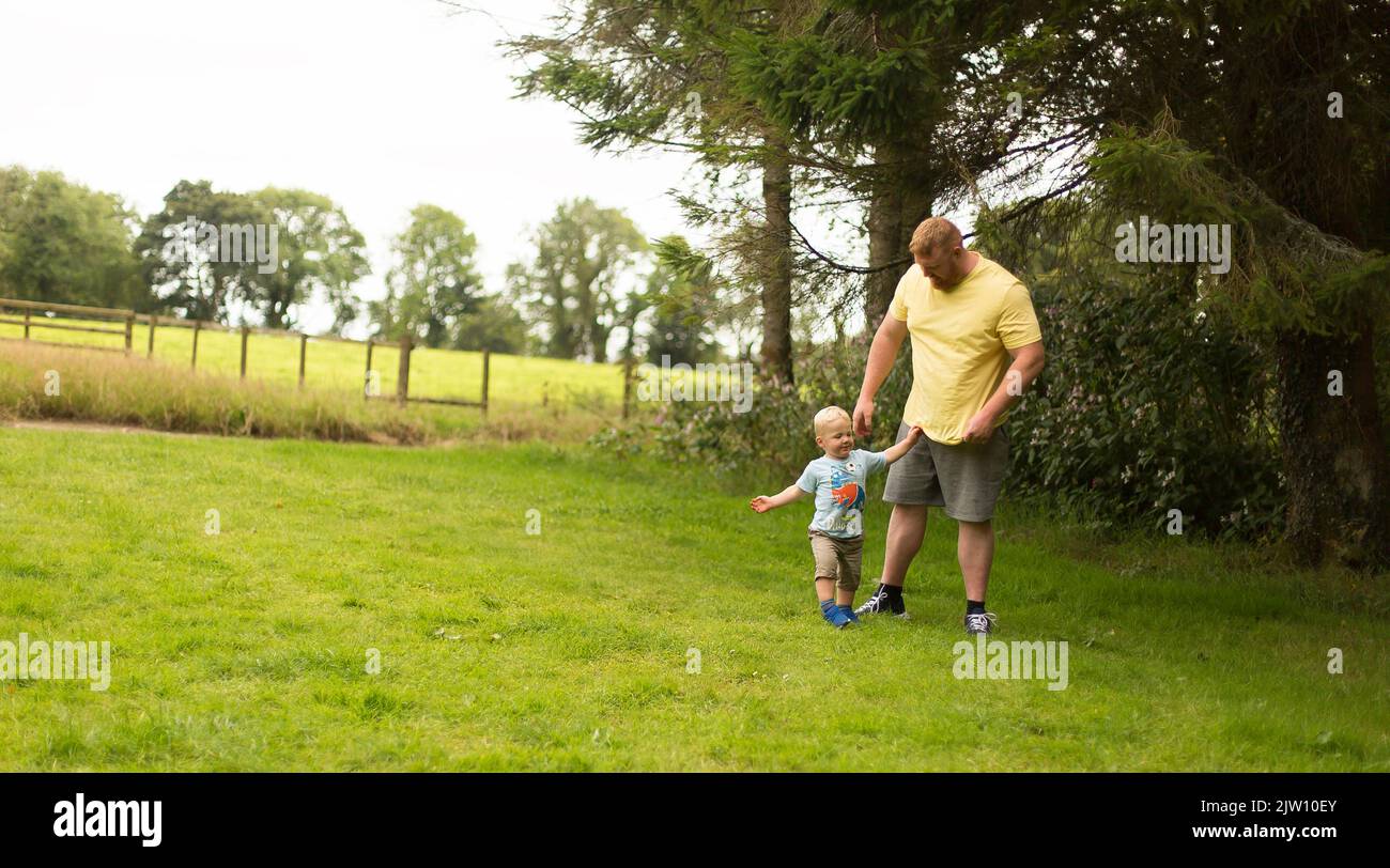Vater und Sohn stehen auf Gras im Freien miteinander. Stockfoto