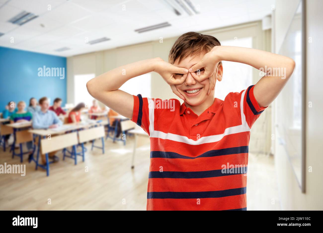 Glücklicher Student Junge macht Fingerbrillen in der Schule Stockfoto