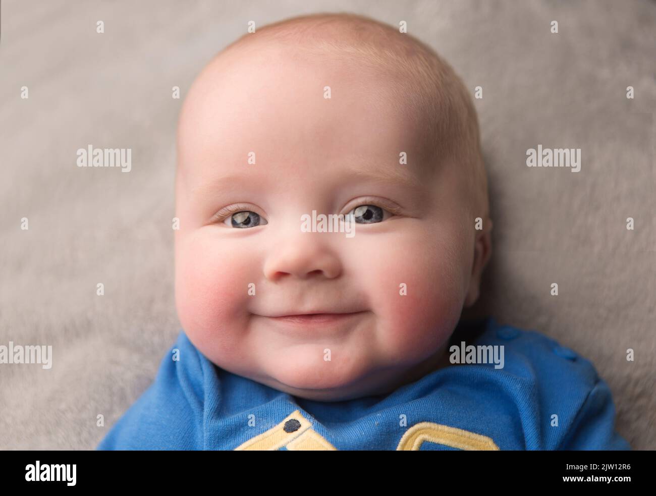 Kaukasischer Junge, lächelnd in die Kamera, während er sich hinlegt, benutzte Studiolicht. Stockfoto