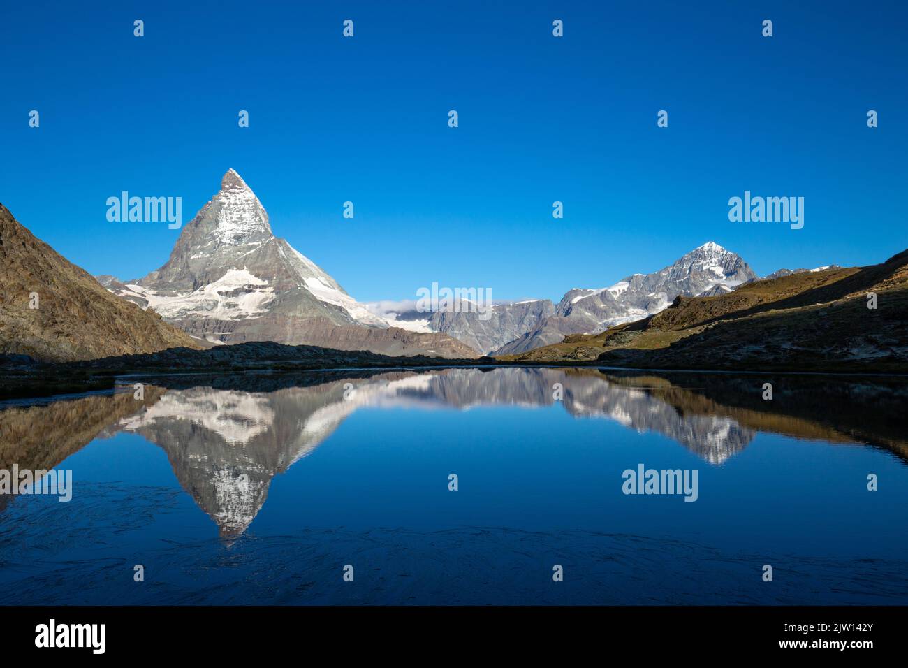 Das majestätische Matterhorn, der berühmteste Berg der Schweiz, spiegelt sich am frühen Morgen im Riffelsee in einer überwältigenden Landschaft wider. Stockfoto