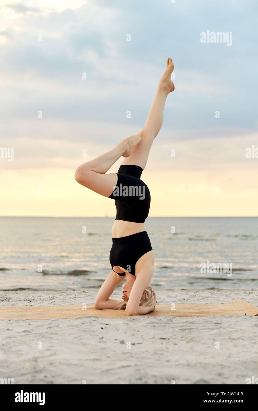 Frau macht Yoga Kopfstand am Strand Stockfoto