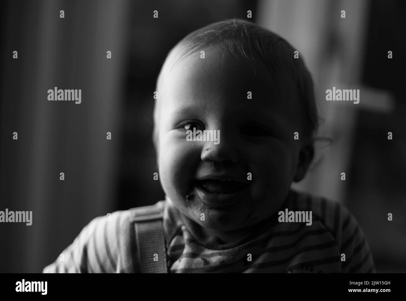 Kaukasisches Kleinkind männlich lächelt mit einem halb beleuchteten Gesicht, schwarz-weiß-Bild. Stockfoto