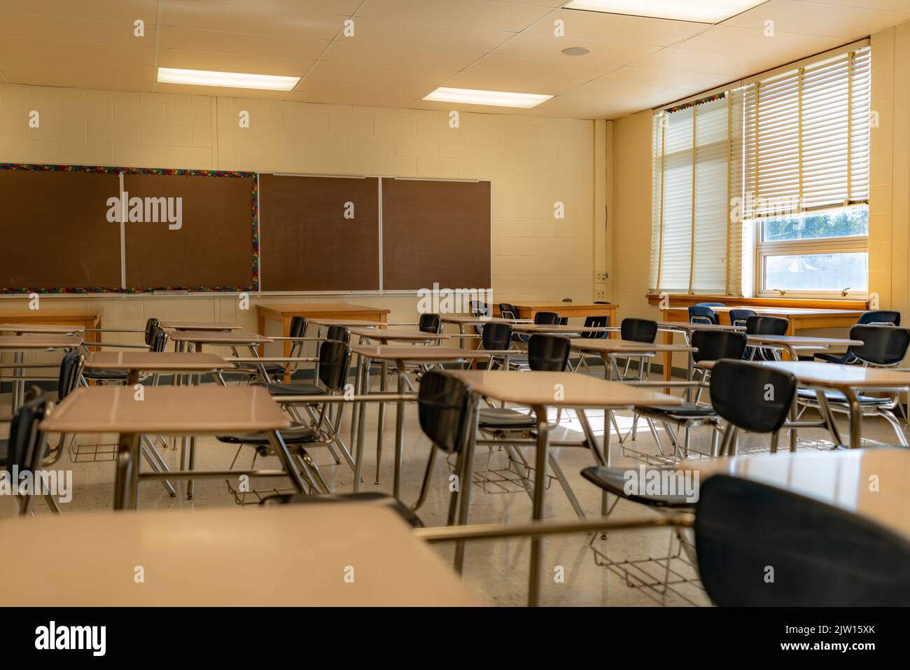 Beispiel eines leeren, unscheinbaren Klassenzimmers der US High School mit Schreibtischen. Stockfoto