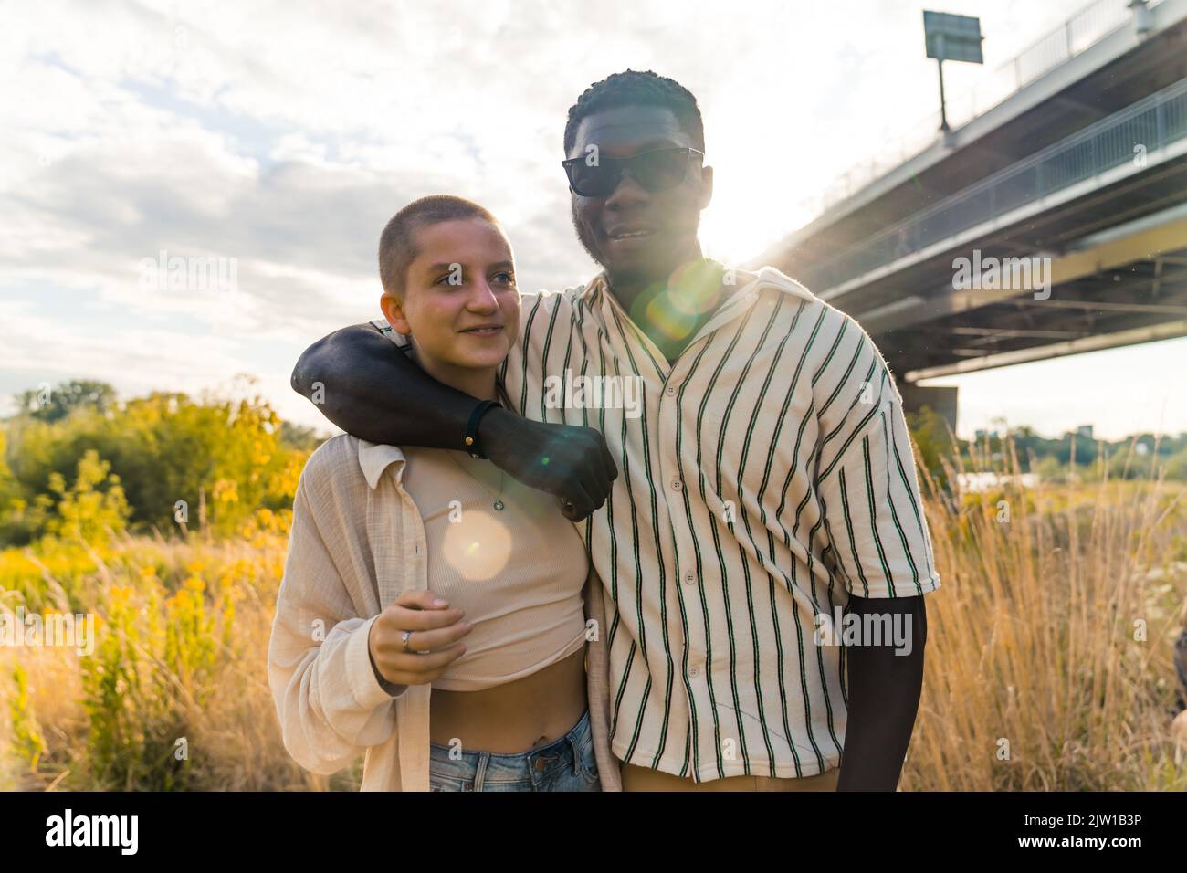 Enge gemischte Rasse Freundschaft. Junger glücklicher afrikanischer Mann und kaukasische Frau umarmen und lächeln und genießen einen sonnigen Sommertag in der Nähe der Natur. Hochwertige Fotos Stockfoto