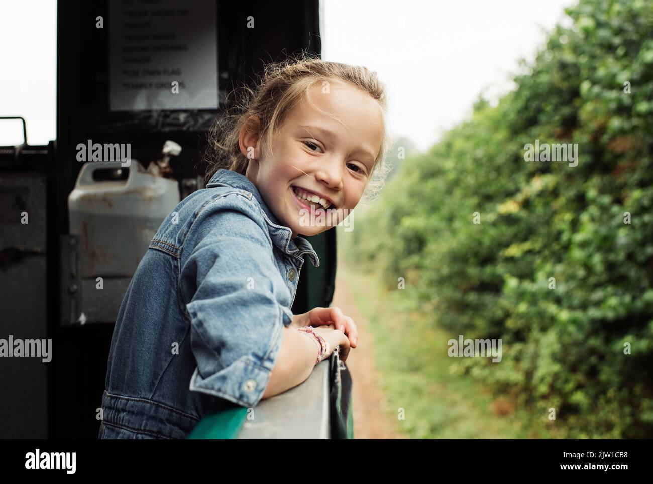 Porträt eines jungen Mädchens, das glücklich auf einem Traktor reitet Stockfoto