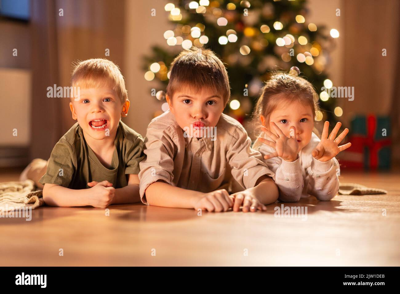 Glückliche Kinder liegen zu weihnachten zu Hause auf dem Boden Stockfoto