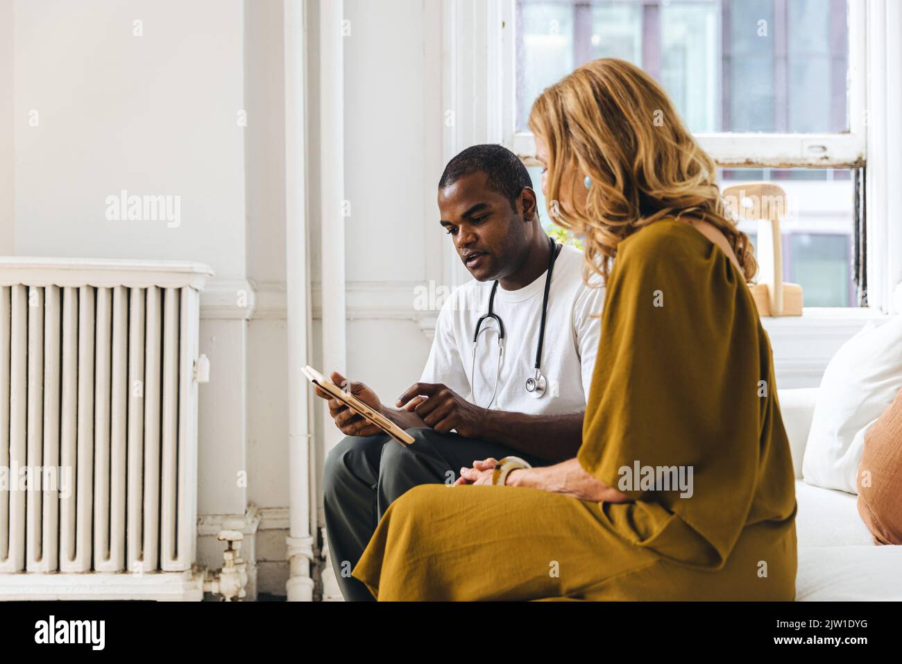 Arzt erklärt reifen Patienten über Krankenakten auf Tablet-PC in der Klinik Stockfoto