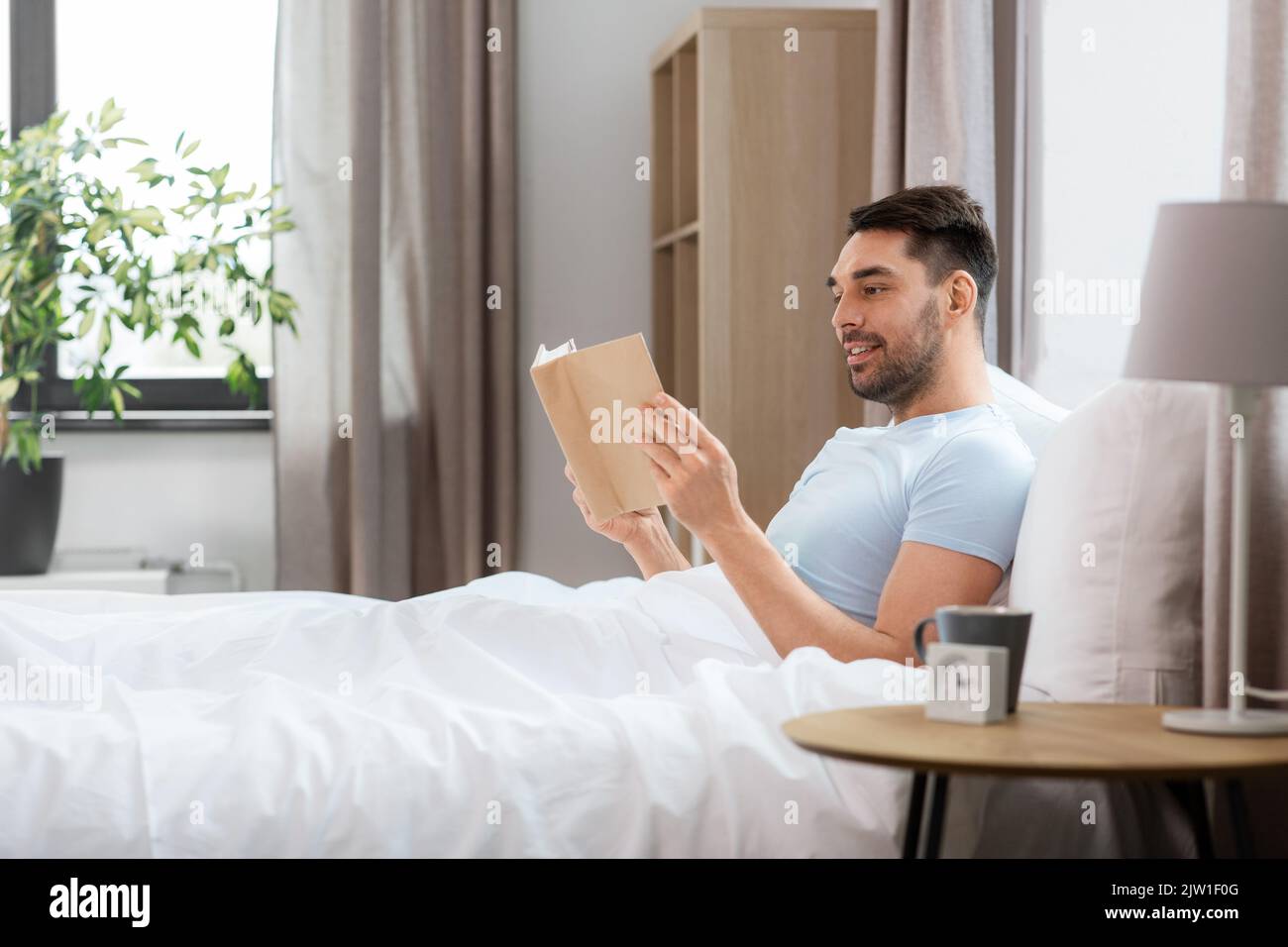 Mann lesen Buch im Bett zu Hause. Stockfoto