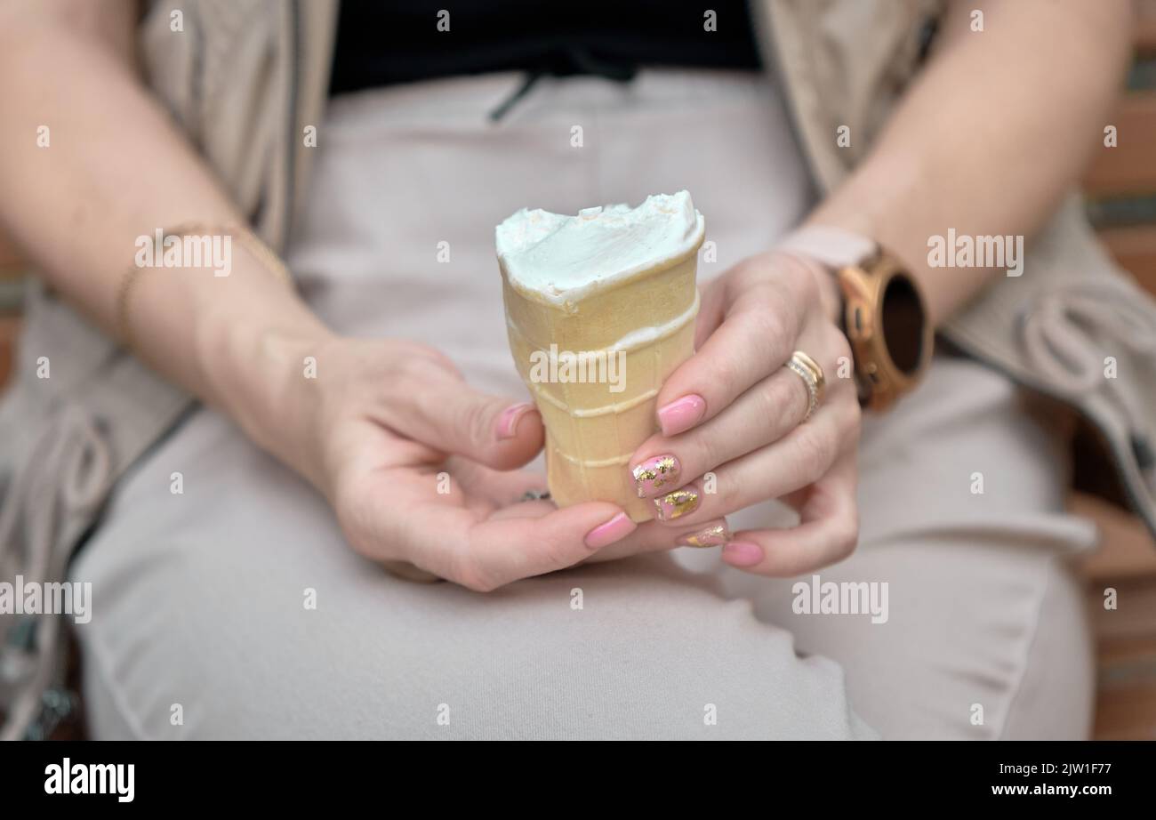 Damenhänden mit Eiscreme im Waffelbecher. Stockfoto