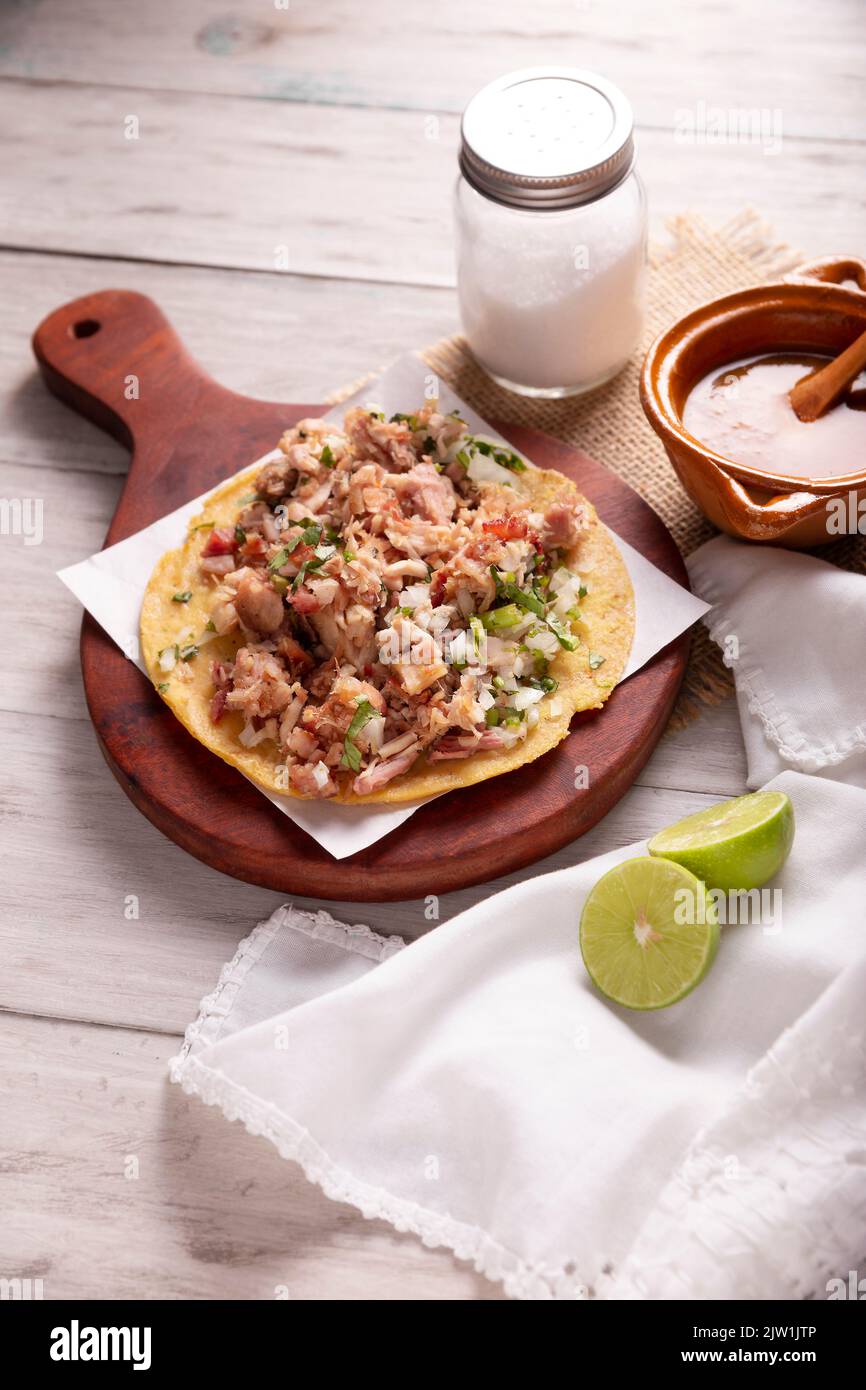 Taco de Carnitas. Maismehl-Tortilla mit frittiertem Schweinefleisch. Traditionelle mexikanische Vorspeise, begleitet von Koriander, Zwiebel und heißer Sauce. Stockfoto