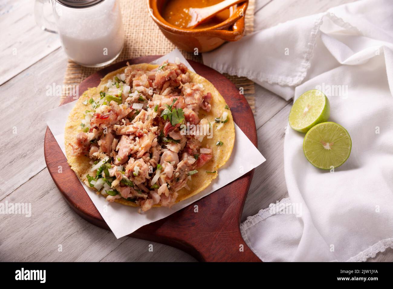 Taco de Carnitas. Maismehl-Tortilla mit frittiertem Schweinefleisch. Traditionelle mexikanische Vorspeise, begleitet von Koriander, Zwiebel und heißer Sauce. Stockfoto