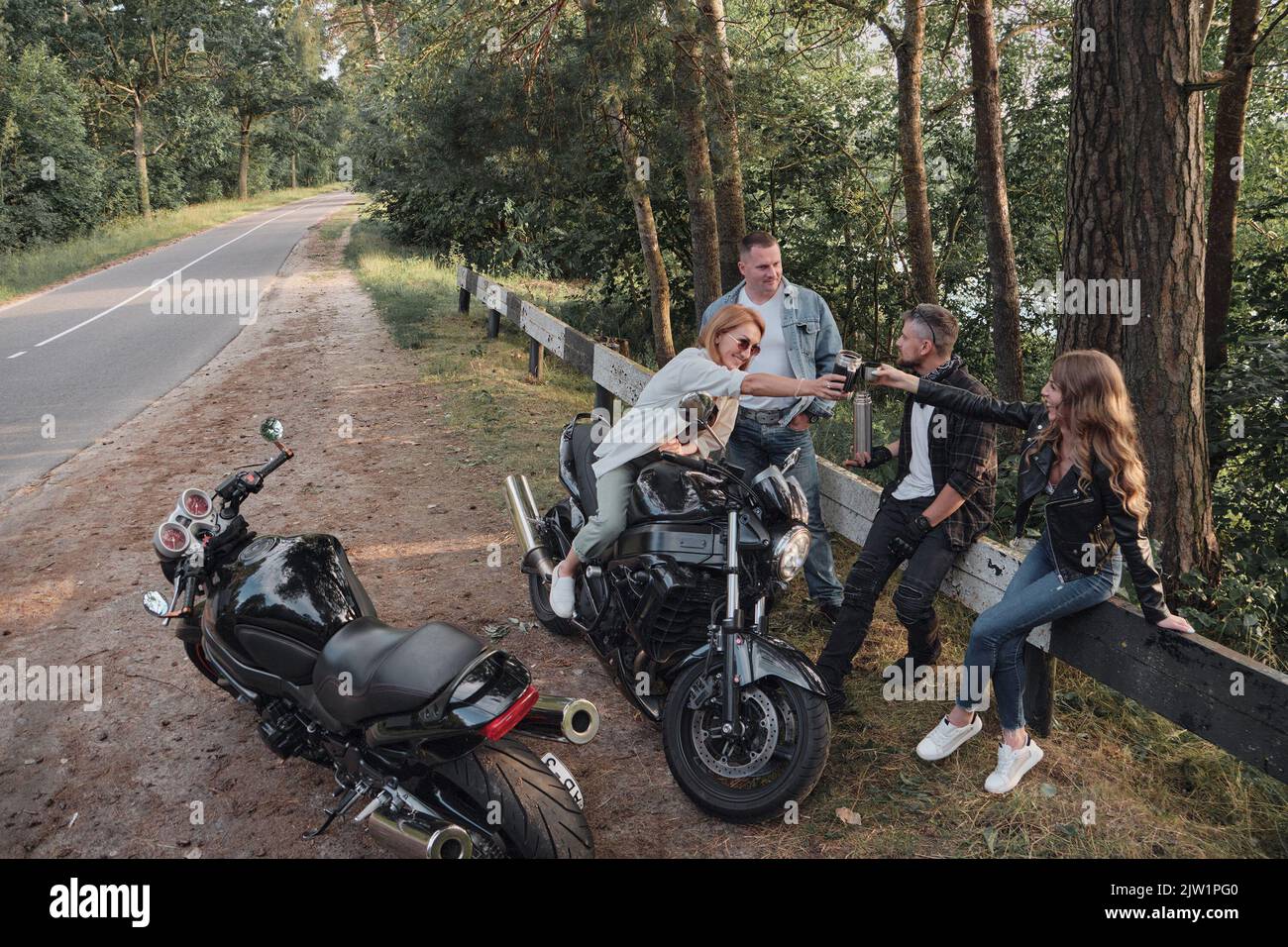 Eine Gruppe von Freunden reist zusammen auf Motorrädern, hält am Straßenrand, hat Spaß und trinkt Tee Stockfoto
