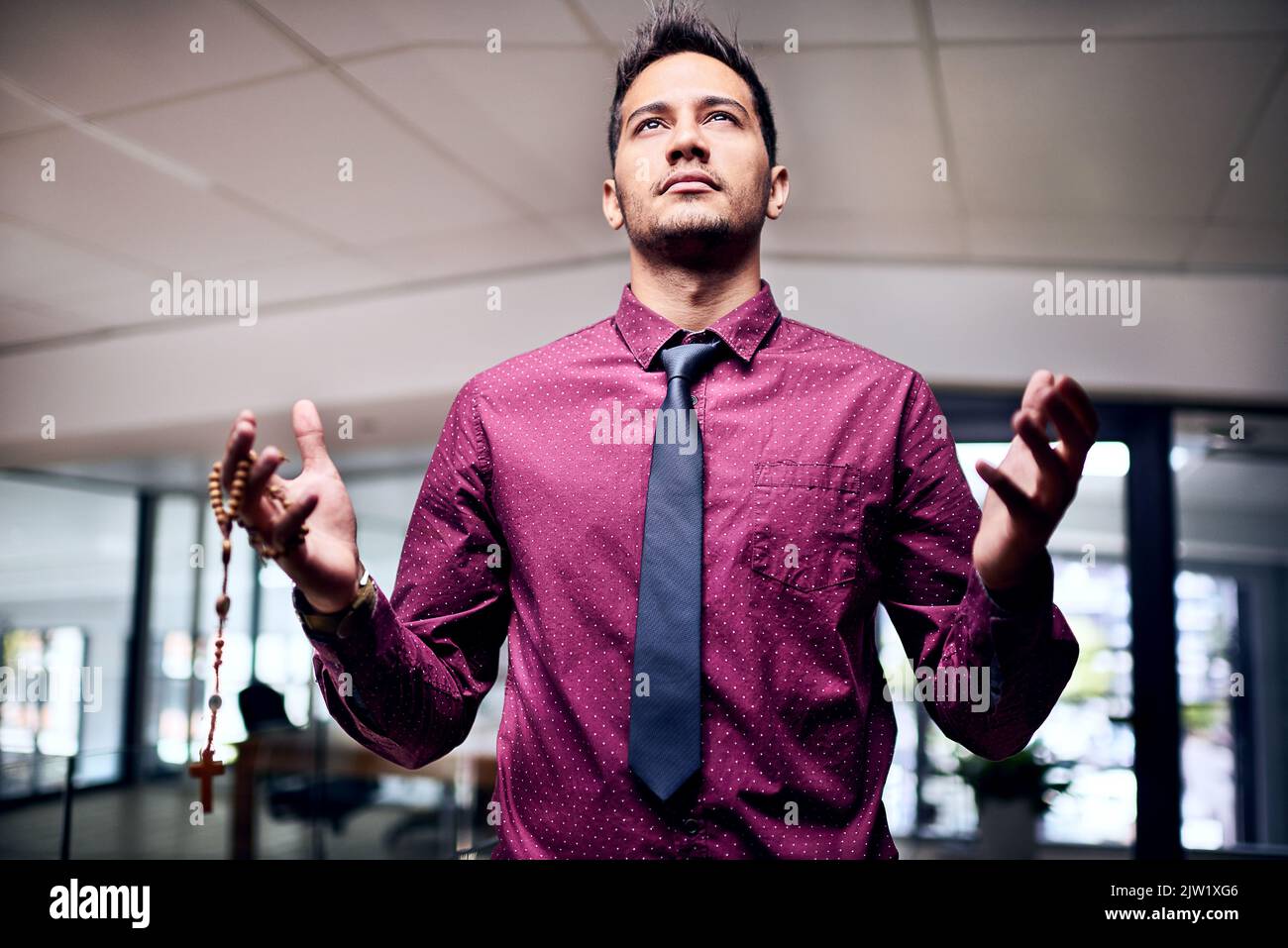 Er weiß, woher sein Erfolg kam: Ein religiöser Geschäftsmann, der in seinem Büro steht. Stockfoto