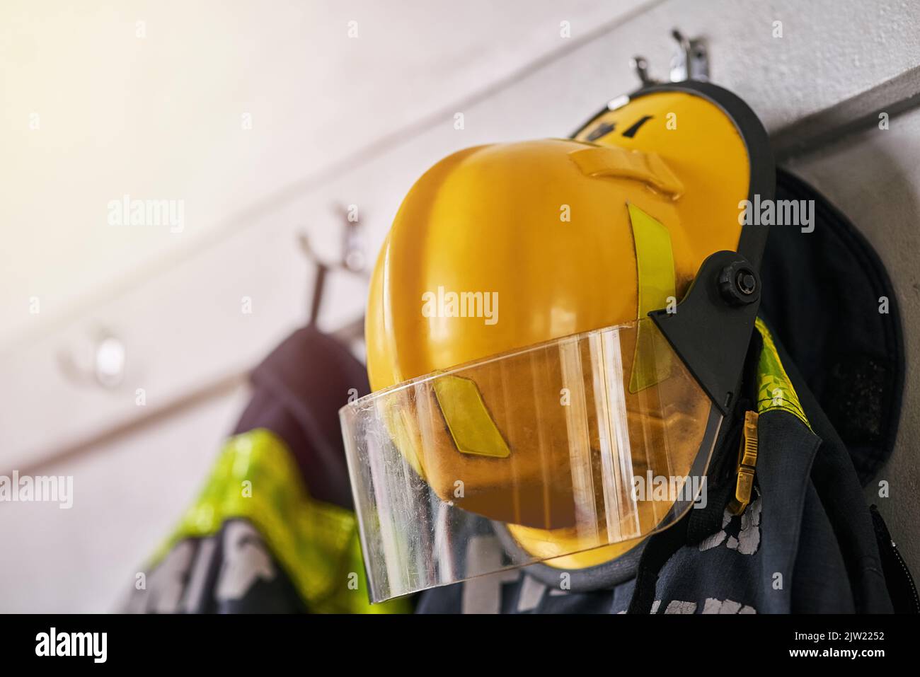 Zur Rettung. Feuerwehrkleidung, die an einer Wand hängt. Stockfoto