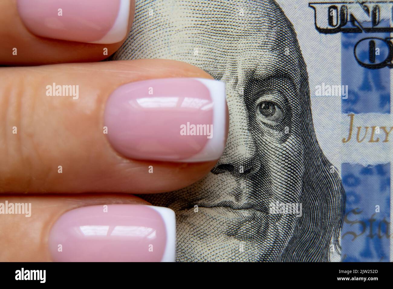 Der Finger einer Frau liegt auf hundert Dollar und verschließt ihr die Augen vor Benjamin Franklin, Finanzen und Wirtschaft, einer Frau auf Geld Stockfoto