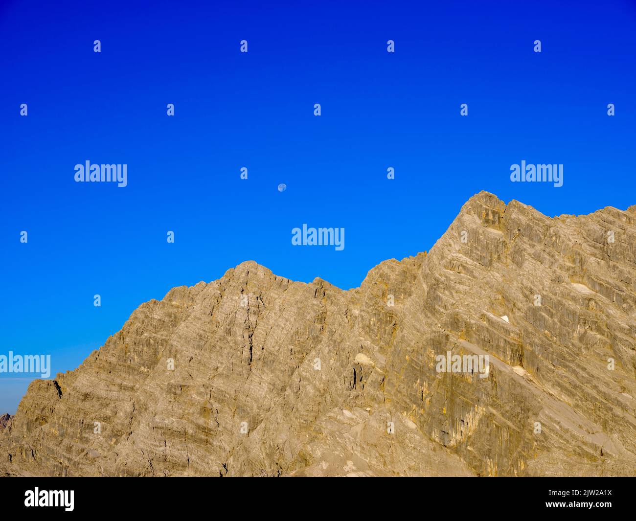 Oberer Teil der Ostwand des Watzmann mit blauem Himmel und Vollmond, Berchtesgadener Alpen, Nationalpark Berchtesgaden, Schönau am Königssee Stockfoto