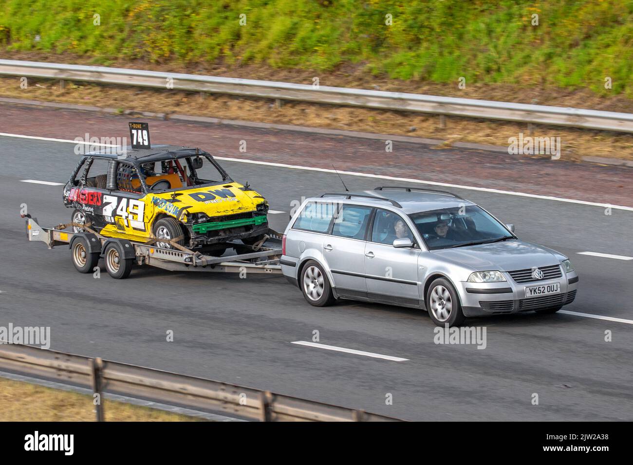 749 T-Bone DW Fotos Stock Car wird auf einem Anhänger von 2002 VW Volkswagen Silver PASSAT Sport TDI 1896cc 6-Gang-Schaltgetriebe abgeschleppt; Fahrt auf der Autobahn M6 UK Stockfoto