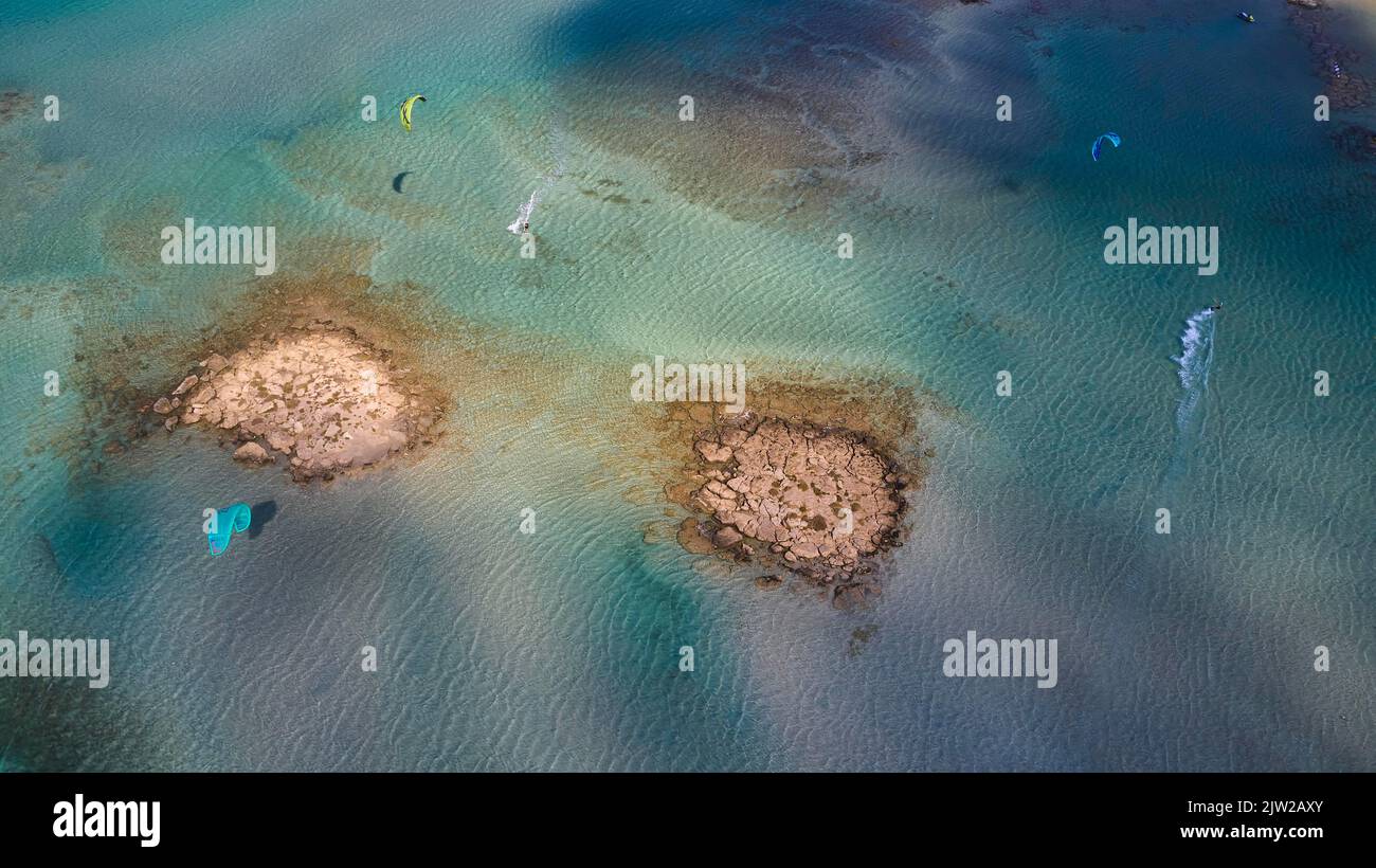 Drohnenschuss, felsige Insel, Kitesurfer, Licht und Schatten, Strand von Elafonissi, Südwest-Kreta, Insel Kreta, Griechische Inseln, Griechenland Stockfoto