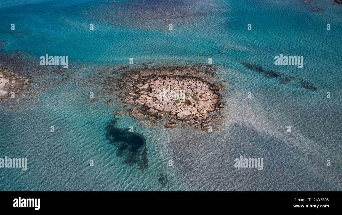 Dronen-Luftaufnahme, schräg, Detail, felsige Insel im seichten Wasser der Lagune, türkisfarbenes Meer, meergrün, Strand von Elafonissi, südwestlich von Kreta, Insel Stockfoto