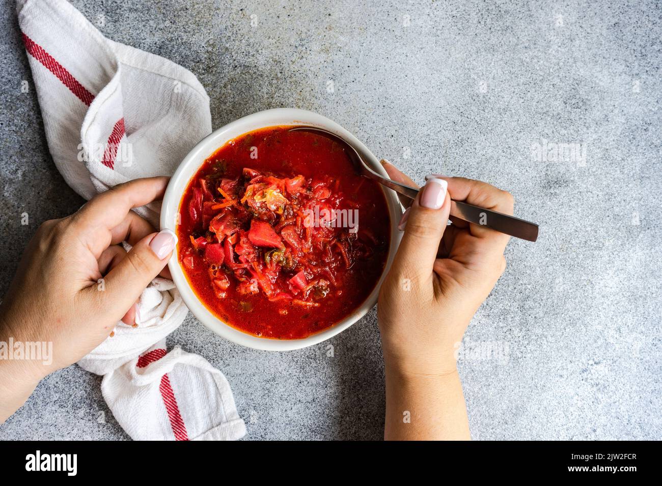 Draufsicht Ernteguthände mit ukrainischem roten Beetroot-Borscht, serviert in der Schüssel auf rustikalem Hintergrund Stockfoto