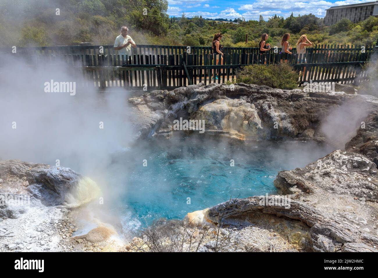 Touristen kommen an einem Pool kochendes Wasser im Whakarewarewa Geothermal Reserve, Rotorua, Neuseeland vorbei Stockfoto