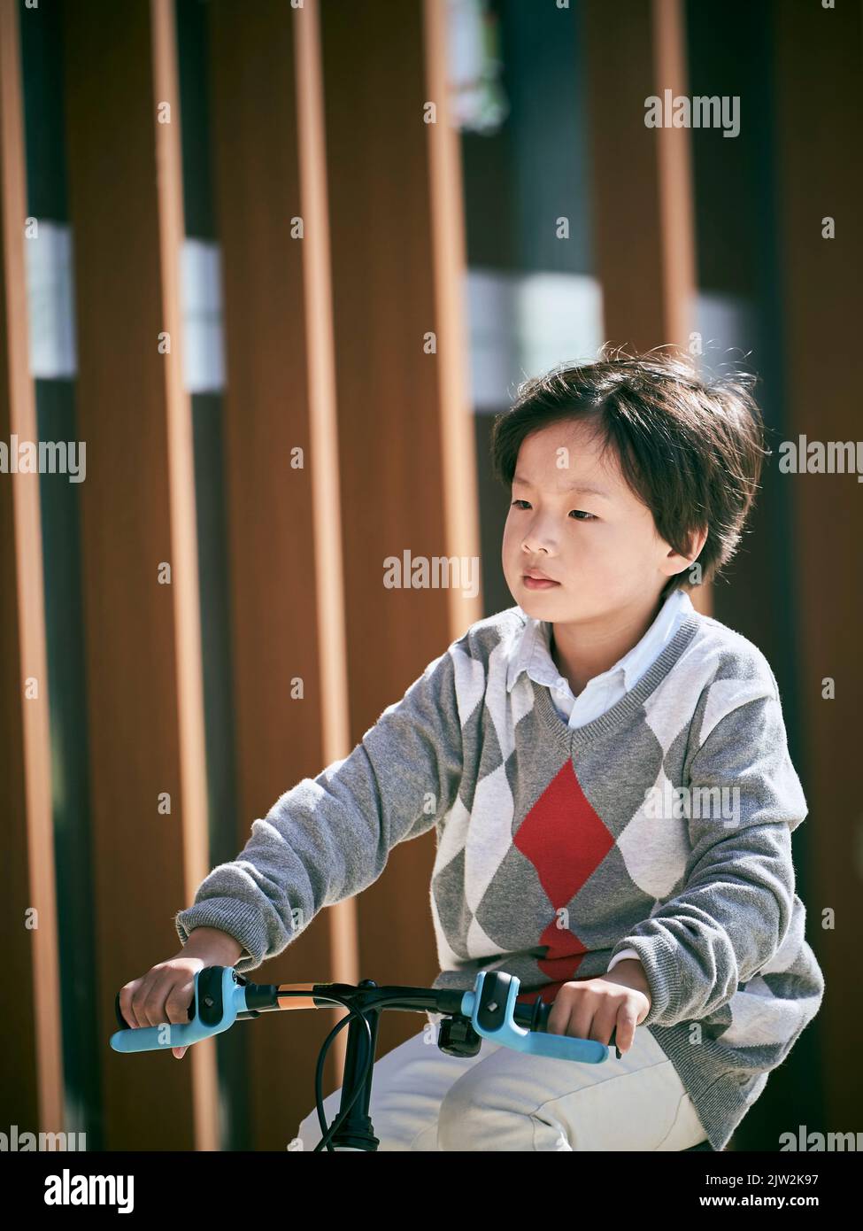 Fünf Jahre alter asiatischer kleiner Junge, der im Freien Fahrrad fährt Stockfoto